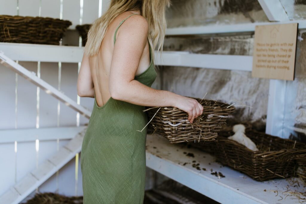 crop woman with wicker basket near white hen in coop