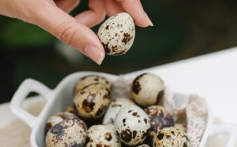 woman with spotty quail eggs in ceramic pan