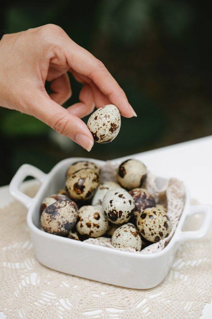 woman with spotty quail eggs in ceramic pan